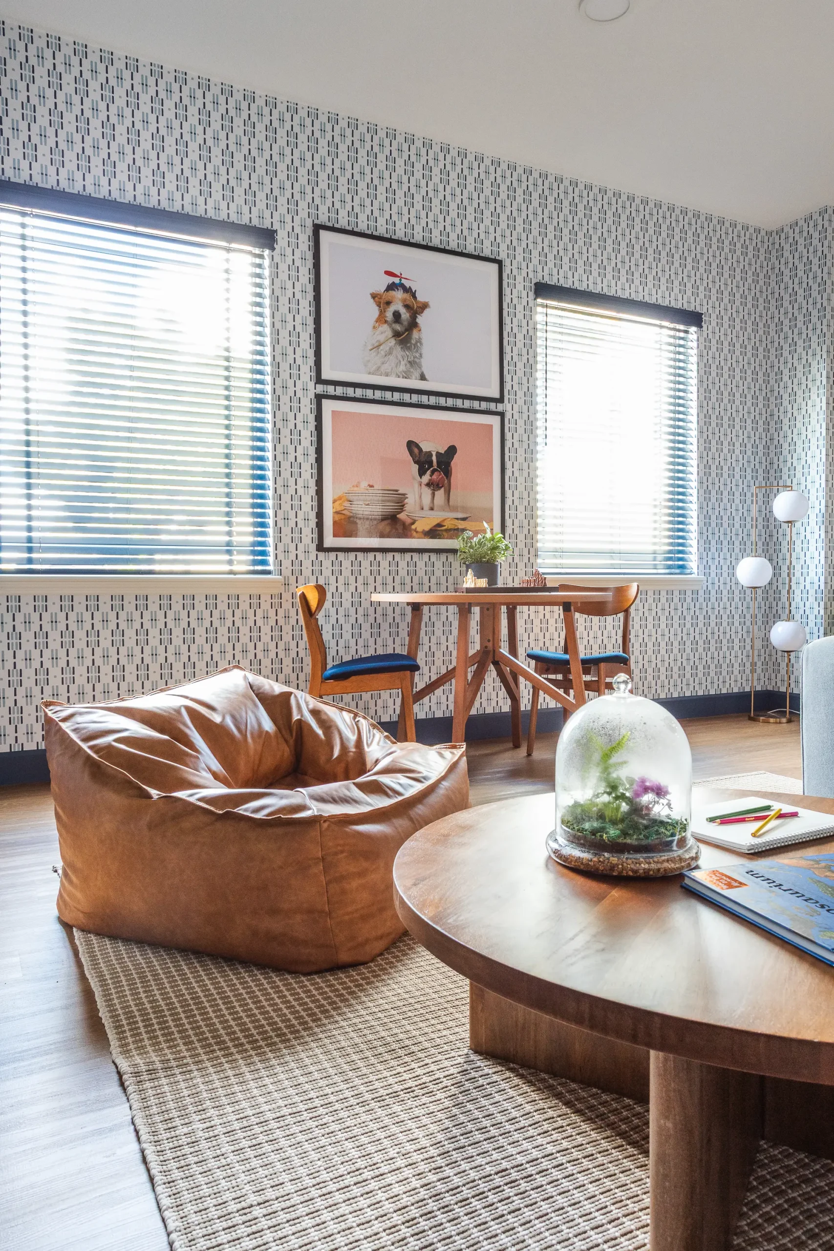 Cozy therapy room corner with a leather bean bag chair, round wooden coffee table, and framed dog portraits on patterned wallpaper